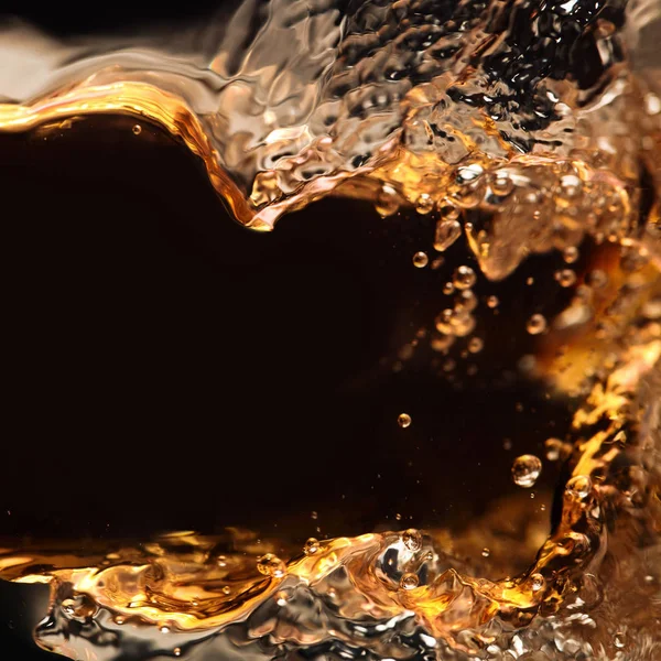 Splashing of alcoholic drink on a black background — Stock Photo, Image