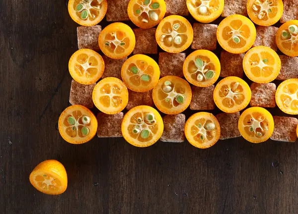 Výseče kumquat s kousky hnědého cukru, pohled shora — Stock fotografie