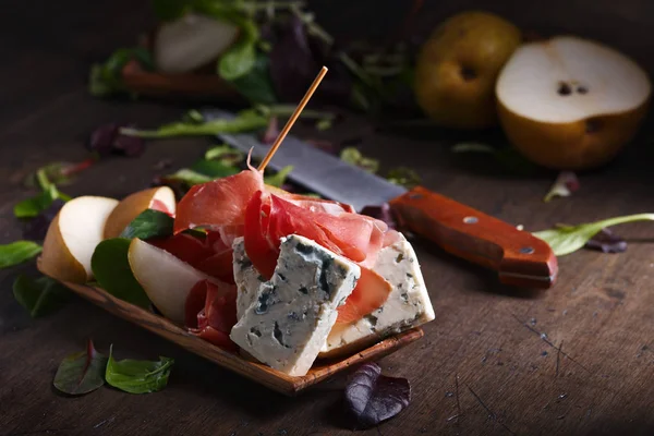 Plísňový sýr s parmskou šunkou a hruškou na dřevěný stůl — Stock fotografie