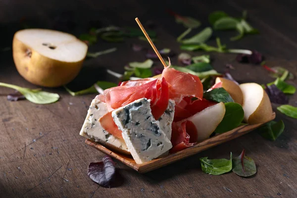 stock image blue cheese with prosciutto and pear on a wooden table