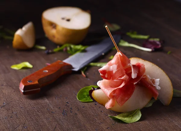 Prosciutto, körte, egy fából készült asztal — Stock Fotó