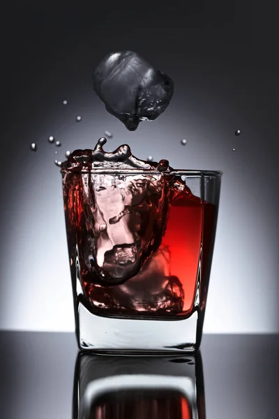 Glass of whiskey with falling ice on a black background — Stock Photo, Image