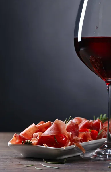 Prosciutto con romero y copa de vino tinto — Foto de Stock