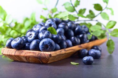 Mutfak masasının üzerinde yeşil yaprakları ile taze sulu yaban mersini . 