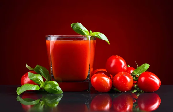 Vaso de jugo de tomate con tomates rojos pequeños — Foto de Stock