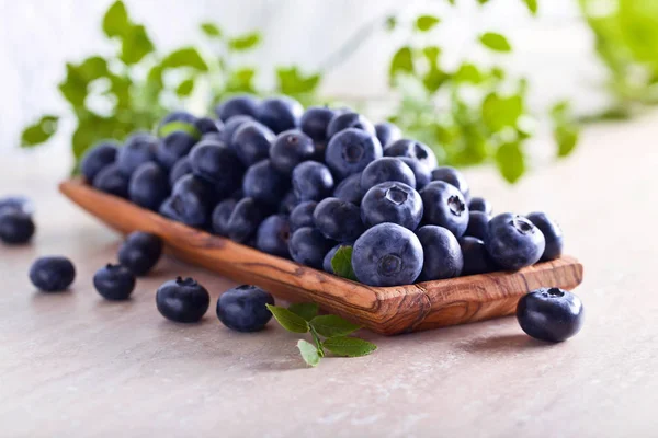 Frische saftige Blaubeeren mit grünen Blättern auf dem Küchentisch . — Stockfoto