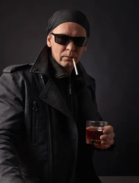 Rocker met glas whiskey en sigaret op zwarte achtergrond. — Stockfoto