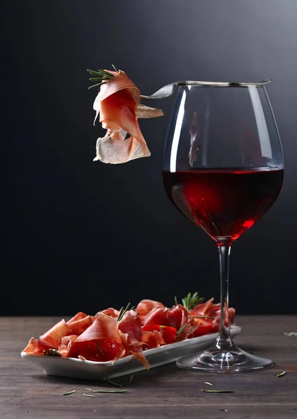 Прошутто с розмарином и бокалом красного вина — стоковое фото