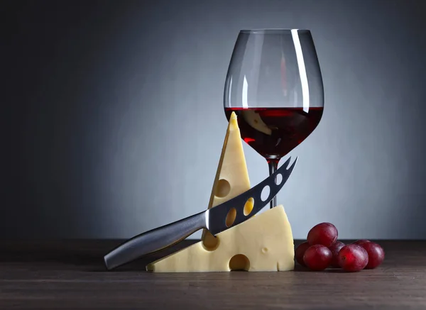 Cheese and red wine on a old wooden table — Stock Photo, Image