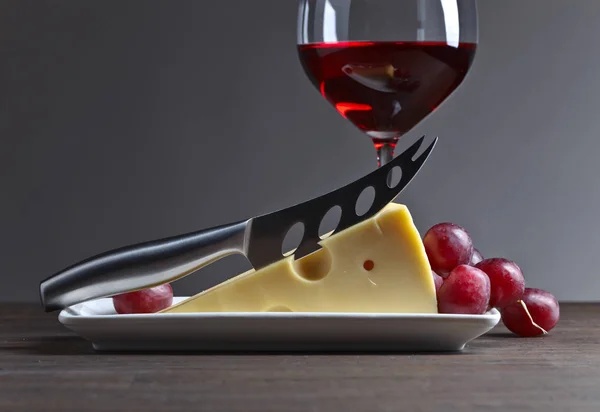 Queso y vino tinto sobre una vieja mesa de madera — Foto de Stock