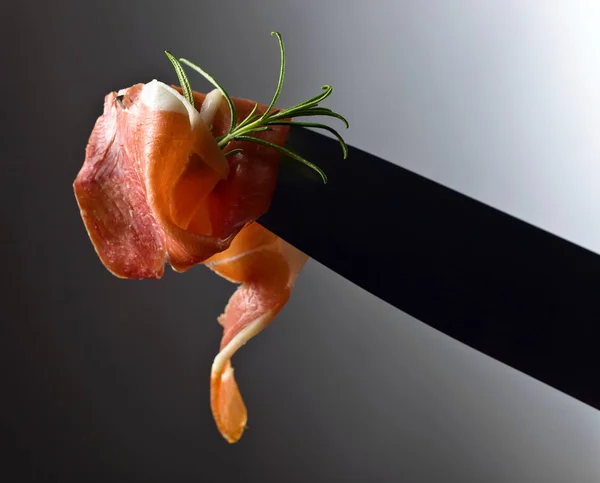 Prosciutto with  rosemary  on a big meat knife. — Stock Photo, Image