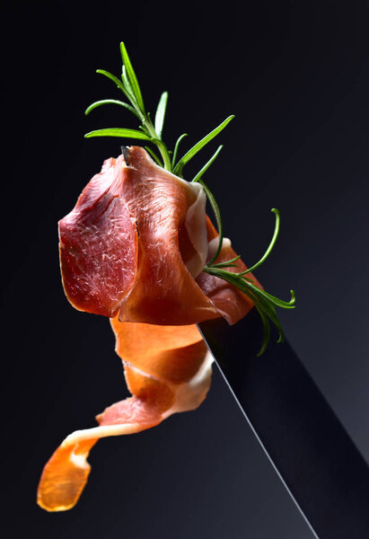  Prosciutto with  rosemary  on a big meat knife. 