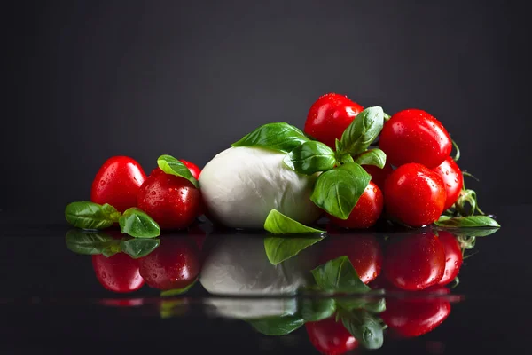 Queso mozzarella con albahaca y tomate sobre mesa negra — Foto de Stock