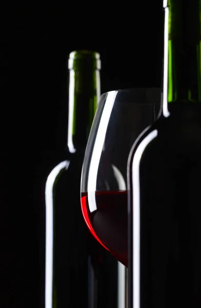 Bottles and glass of red wine on a black background . — Stock Photo, Image