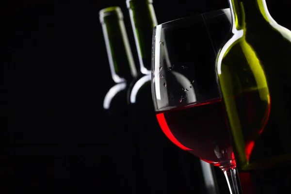 Botellas y copa de vino tinto sobre fondo negro  . —  Fotos de Stock
