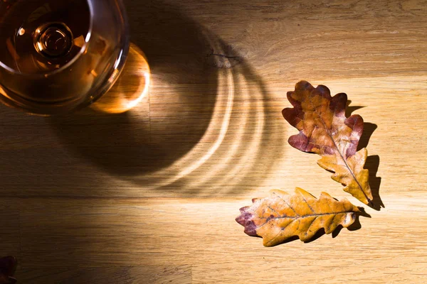 Snifter of brandy and dried oak leaves — Stock Photo, Image