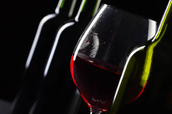 Botellas y copa de vino tinto sobre fondo negro  . — Foto de Stock