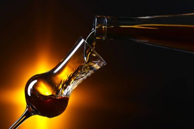 Alkol koyu arka plan üzerine bir bardak içine dökme
