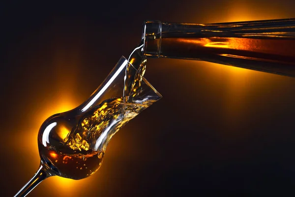 Наливание алкоголя в стакан на тёмном фоне — стоковое фото