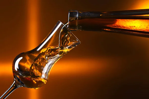 Versare l'alcol in un bicchiere su sfondo scuro — Foto Stock