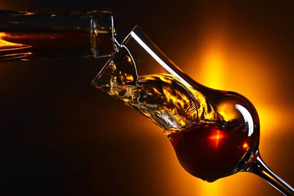 Pouring alcohol into a glass on dark background — Stock Photo, Image