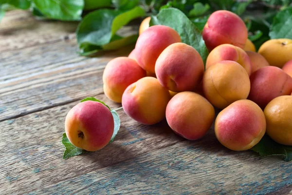 Juicy fresh apricots with leaves on old wooden table . — Stock Photo, Image