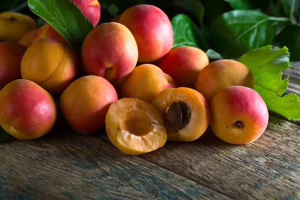 Juicy fresh apricots with leaves on old wooden table . — Stock Photo, Image