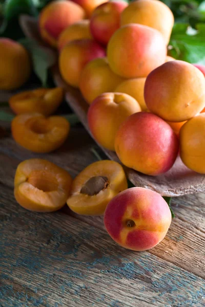 Соковиті свіжі абрикоси з листям на старому дерев'яному столі  . — стокове фото