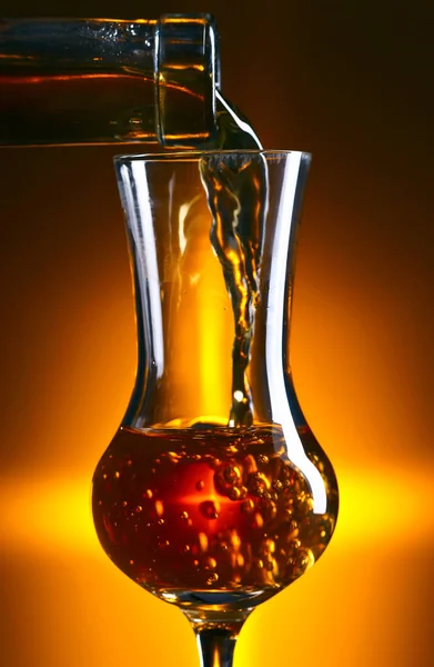 Verter alcohol en un vaso sobre fondo oscuro — Foto de Stock