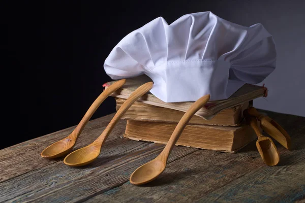 Old culinary books , chef hat and wooden spoons . — Stock Photo, Image