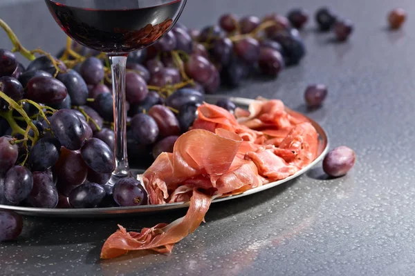 Prosciutto met druiven en rode wijn . — Stockfoto