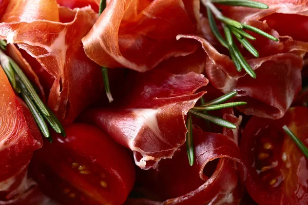 Prosciutto with  rosemary and tomato on a wooden table — Stock Photo, Image