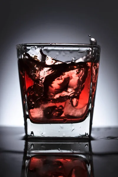 黒を背景に氷とウイスキーのグラス — ストック写真