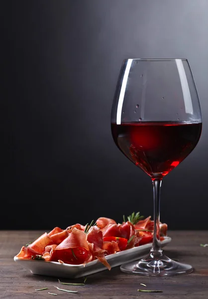 Prosciutto con romero y copa de vino tinto — Foto de Stock