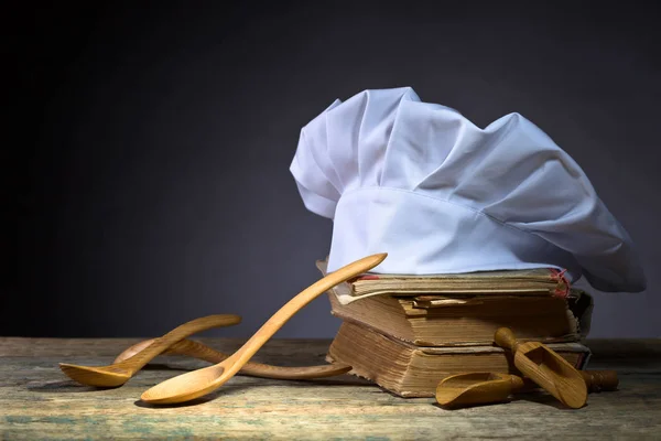 Old culinary books , chef hat and wooden spoons . — Stock Photo, Image