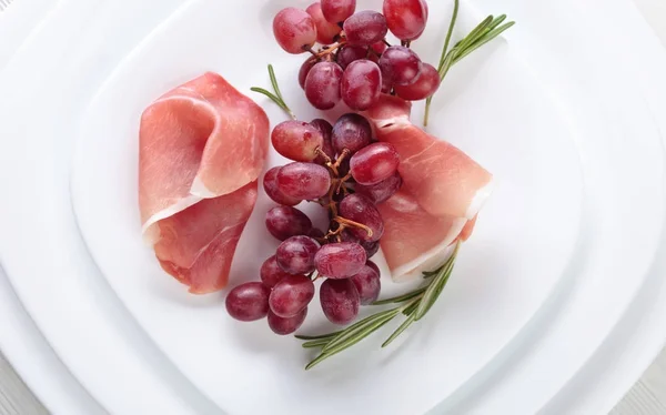 Jamon serrano with rosemary and grape . — Stock Photo, Image