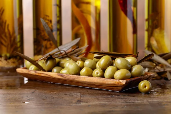 Groene olijven en olijfolie flessen . — Stockfoto