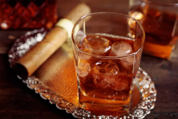 Vaso de whisky y cigarro sobre una vieja mesa de madera . — Foto de Stock