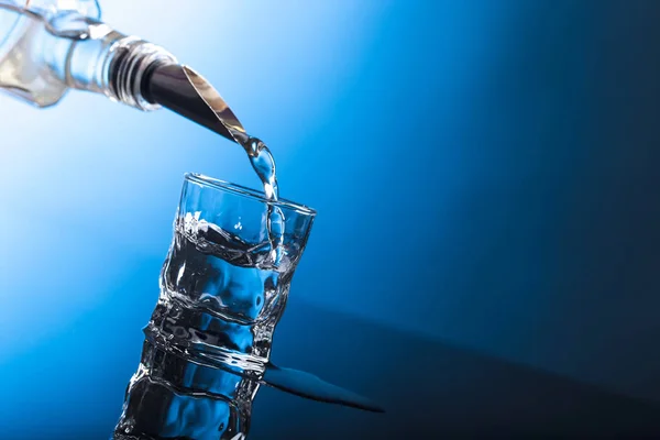 Vodka que vierte de la botella en un vaso en un bar . — Foto de Stock