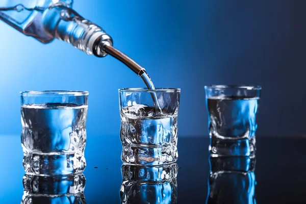 Vodka versando dalla bottiglia in un bicchiere in un bar . — Foto Stock