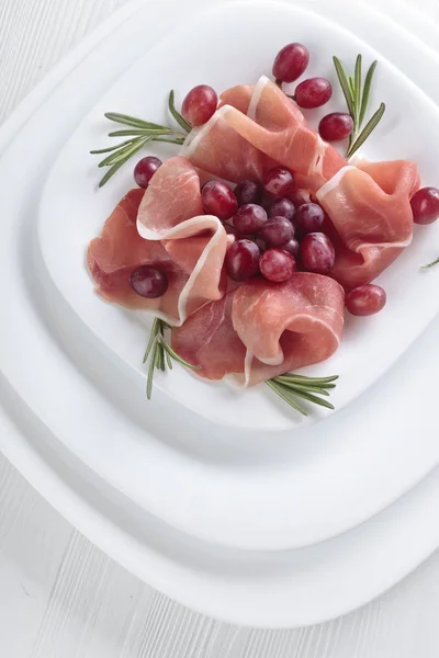 Jamon serrano with rosemary and grape . — Stock Photo, Image