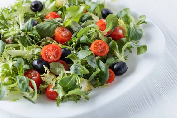 Ensalada verde con tomates y aceitunas negras . — Foto de Stock