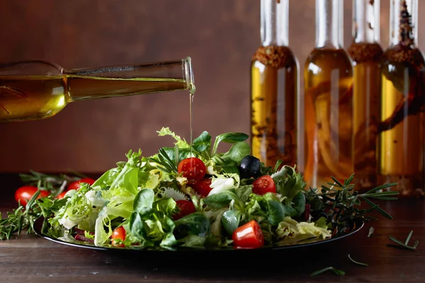 Зеленый салат с оливковым маслом, выливающимся из маленькой бутылки . — стоковое фото