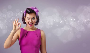 Tamam işaret gösteren bir mor elbiseli mutlu kadın.