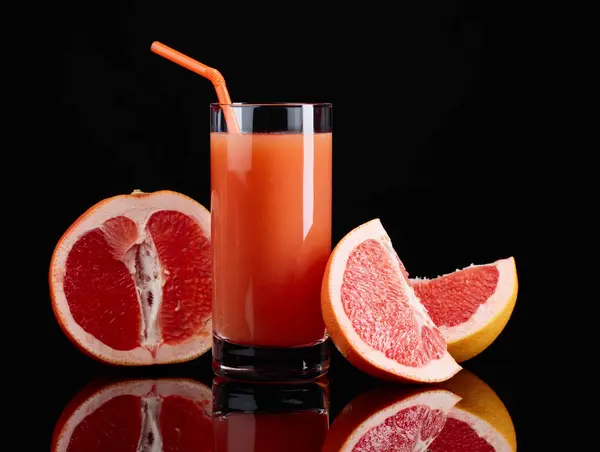 Sklo grapefruitový džus a řezu ovoce na černém pozadí. — Stock fotografie