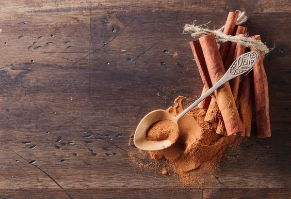 Cinnamon sticks and powder on a old wooden table. — Stock Photo, Image