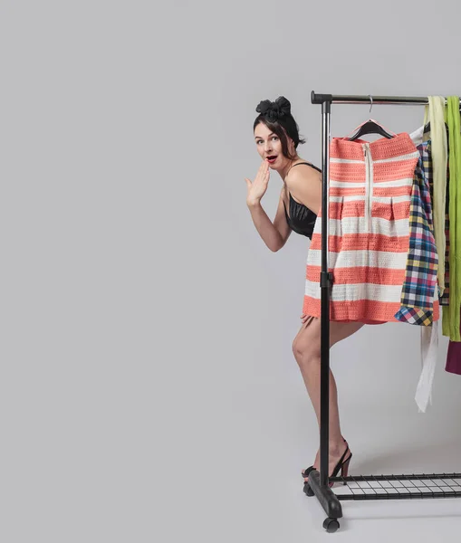 Atraktivní překvapená žena stojící poblíž regály oblečení . — Stock fotografie