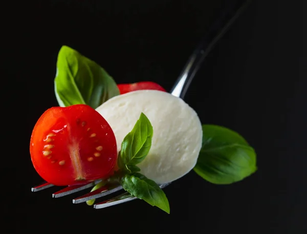 Ser mozzarella z pomidorami cherry i zielonej bazylii na widelcu — Zdjęcie stockowe