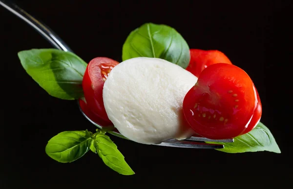 Mozzarella cheese with tomato cherry and green basil on a fork — Stock Photo, Image