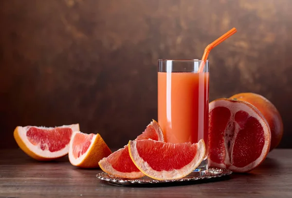 Sklenka čerstvé grapefruitové šťávy a řezu ovoce . — Stock fotografie
